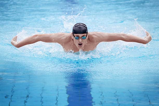Swimmer in cap breathing performing the butterfly stroke